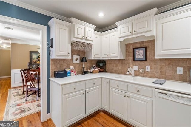 kitchen with dishwasher, tasteful backsplash, light hardwood / wood-style flooring, white cabinets, and ornamental molding