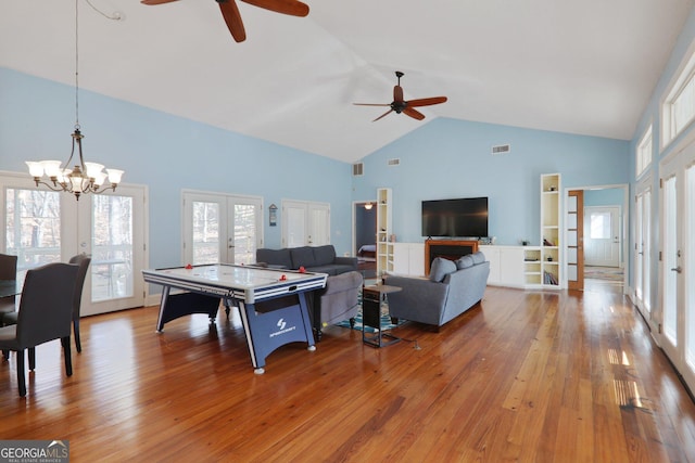 living room featuring light wood-type flooring, french doors, ceiling fan with notable chandelier, and high vaulted ceiling