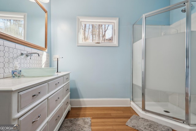 bathroom with tasteful backsplash, vanity, wood-type flooring, and a shower with door