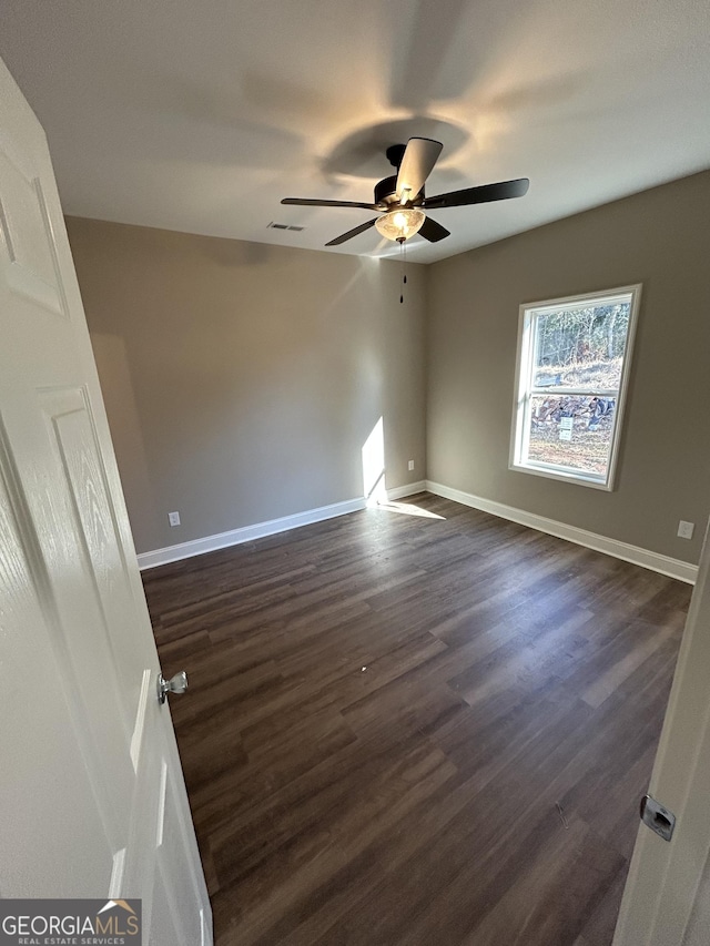 empty room with ceiling fan and dark hardwood / wood-style flooring