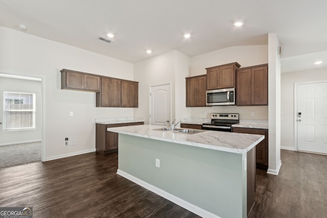 kitchen featuring sink, dark wood-type flooring, stainless steel appliances, light stone counters, and an island with sink