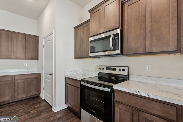 kitchen with light stone counters, stainless steel appliances, and dark wood-type flooring