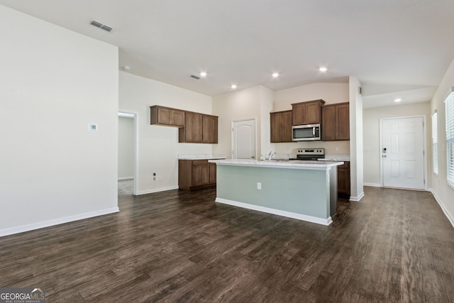 kitchen with a kitchen island with sink, dark wood-type flooring, sink, vaulted ceiling, and stainless steel appliances