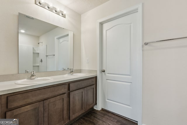 bathroom featuring hardwood / wood-style floors, vanity, a shower, and a textured ceiling