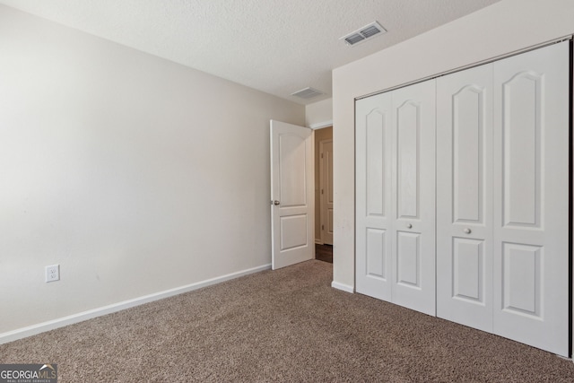 unfurnished bedroom featuring carpet flooring, a textured ceiling, and a closet