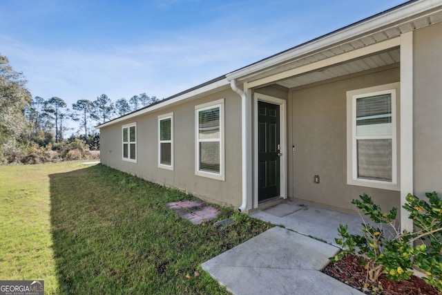 doorway to property featuring a lawn