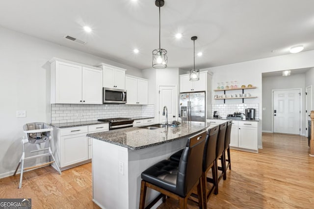 kitchen featuring appliances with stainless steel finishes, tasteful backsplash, sink, a center island with sink, and white cabinets