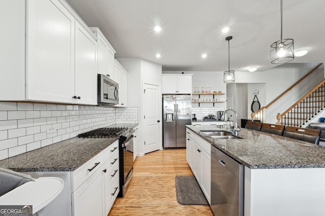 kitchen with pendant lighting, stainless steel appliances, and an island with sink