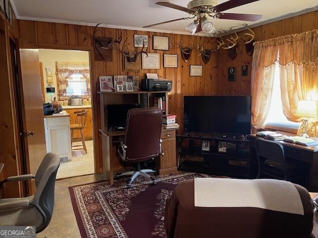 home office featuring ceiling fan, wooden walls, and crown molding