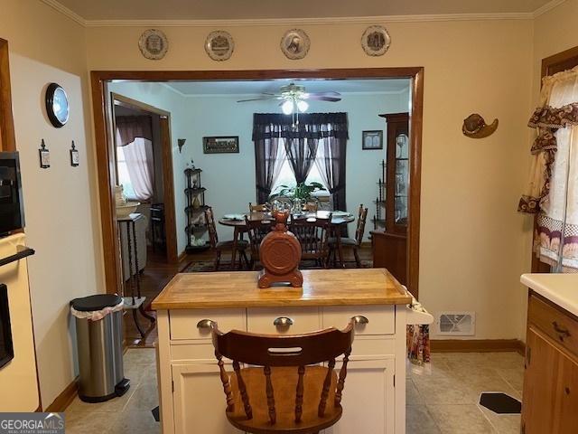 tiled dining area featuring ceiling fan and crown molding