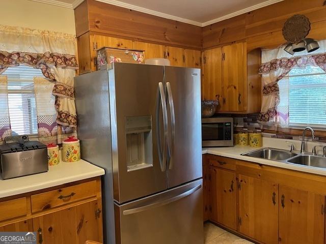 kitchen featuring stainless steel appliances, sink, light tile patterned floors, and crown molding