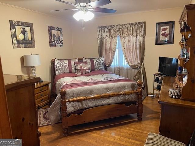 bedroom featuring ceiling fan, ornamental molding, and hardwood / wood-style flooring