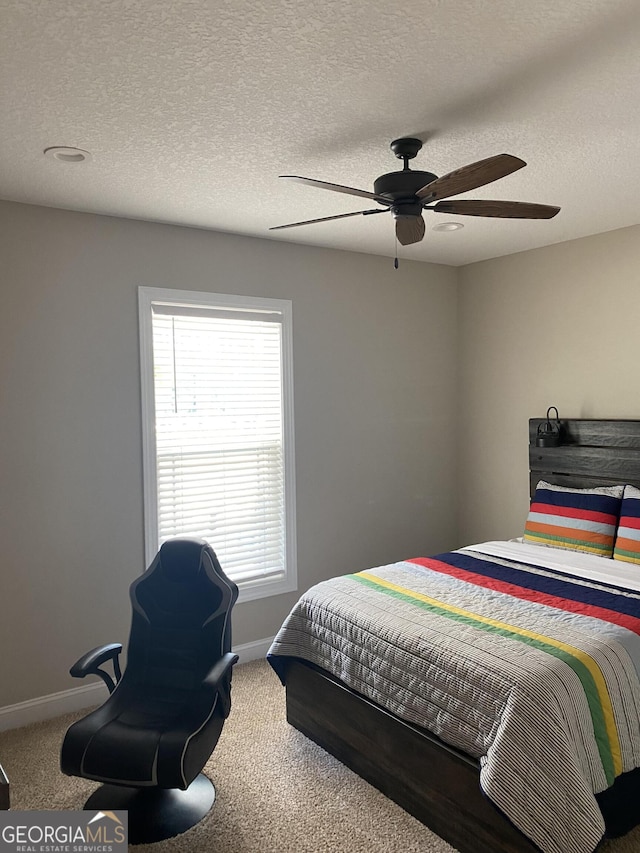 carpeted bedroom with ceiling fan and a textured ceiling