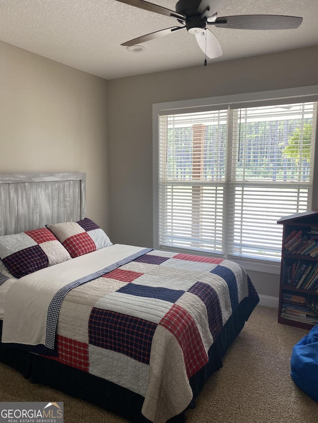 carpeted bedroom featuring ceiling fan and a textured ceiling