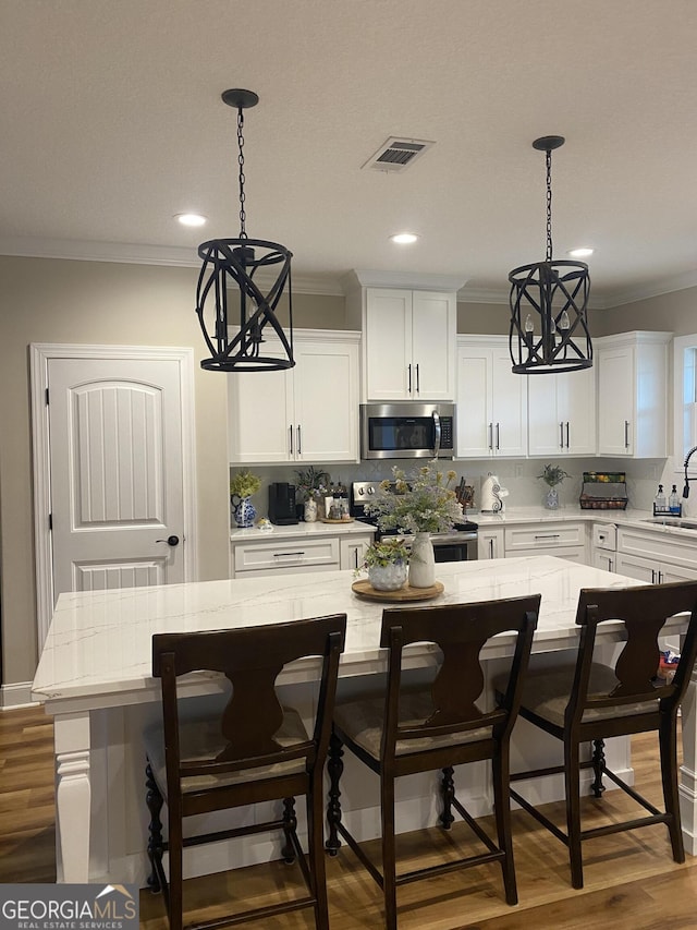 kitchen with a center island, stainless steel appliances, an inviting chandelier, a breakfast bar area, and white cabinets