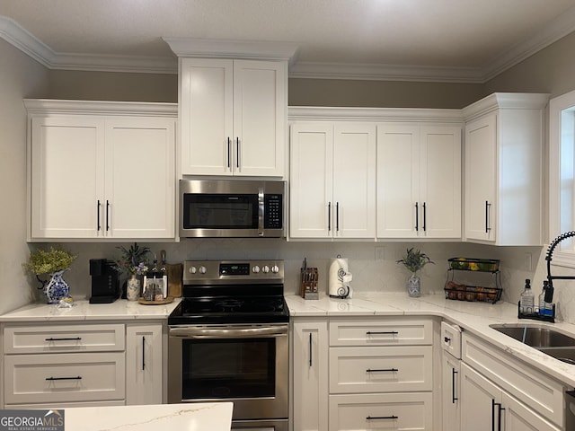 kitchen featuring white cabinetry, sink, light stone counters, crown molding, and appliances with stainless steel finishes