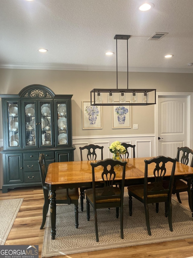 dining area featuring a textured ceiling, crown molding, and light hardwood / wood-style flooring