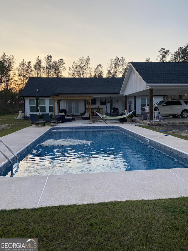 pool at dusk with a patio area