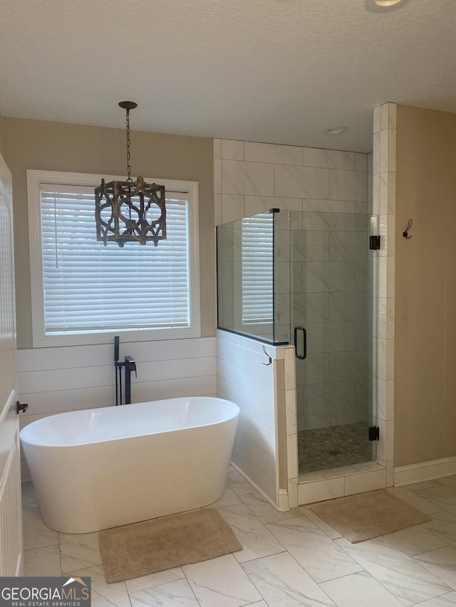 bathroom with separate shower and tub, a textured ceiling, and an inviting chandelier