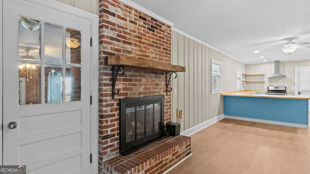 living room featuring light wood-type flooring, a brick fireplace, ceiling fan, and crown molding