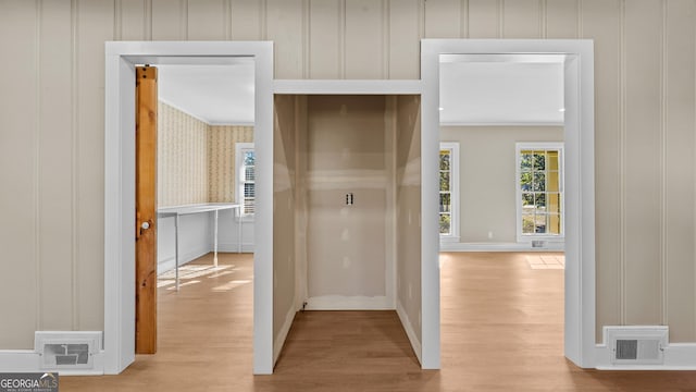 hallway with light hardwood / wood-style flooring and ornamental molding