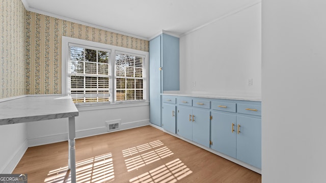 unfurnished office featuring crown molding and light wood-type flooring