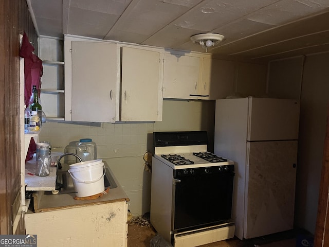 kitchen with white appliances, white cabinetry, and sink