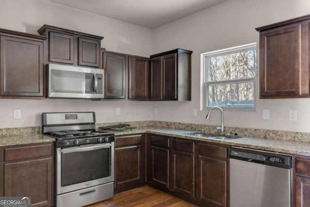 kitchen with appliances with stainless steel finishes, dark brown cabinetry, dark wood-type flooring, and sink