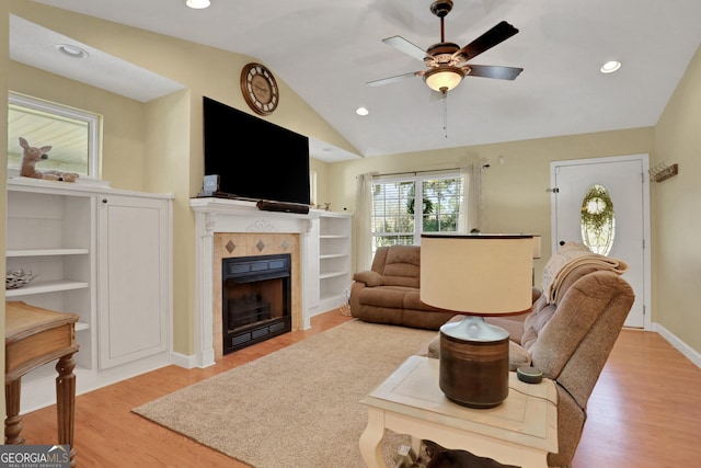 living room with a fireplace, vaulted ceiling, light hardwood / wood-style flooring, and ceiling fan