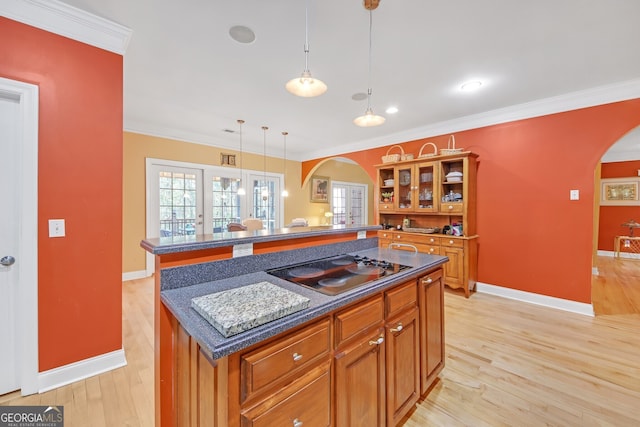 kitchen featuring a kitchen island, hanging light fixtures, ornamental molding, and stovetop