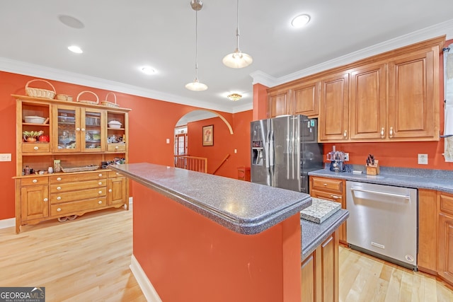 kitchen with appliances with stainless steel finishes, a kitchen island, hanging light fixtures, light hardwood / wood-style flooring, and crown molding