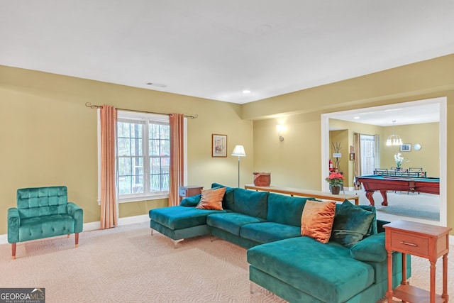 carpeted living room featuring billiards and a notable chandelier