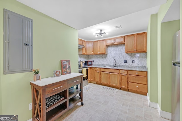 kitchen with appliances with stainless steel finishes, tasteful backsplash, sink, an inviting chandelier, and electric panel