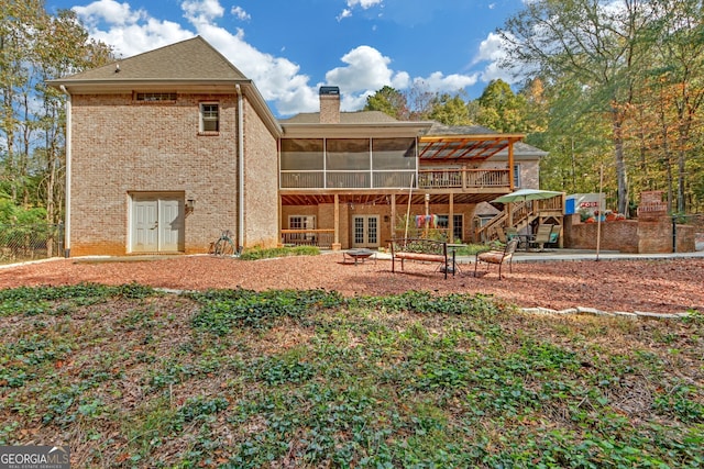 rear view of house featuring a sunroom, a wooden deck, and french doors