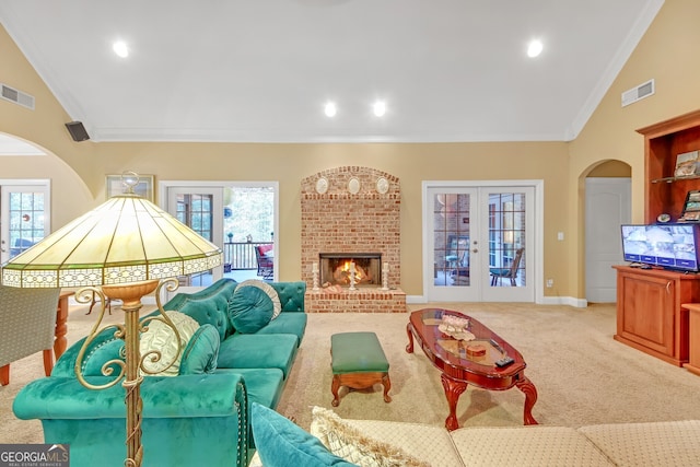 carpeted living room with french doors, a brick fireplace, ornamental molding, and high vaulted ceiling