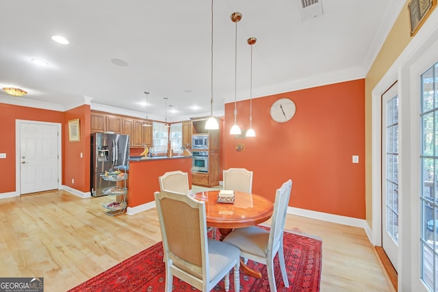 dining space with crown molding and light wood-type flooring