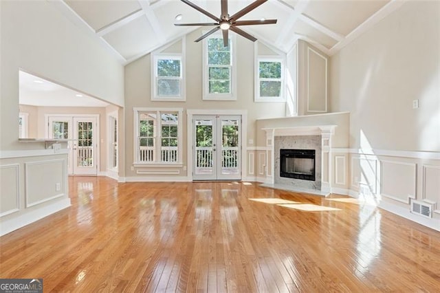 unfurnished living room with a high end fireplace, french doors, hardwood / wood-style flooring, and ceiling fan