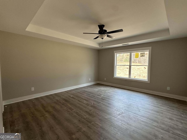 spare room featuring dark hardwood / wood-style flooring, a raised ceiling, and ceiling fan