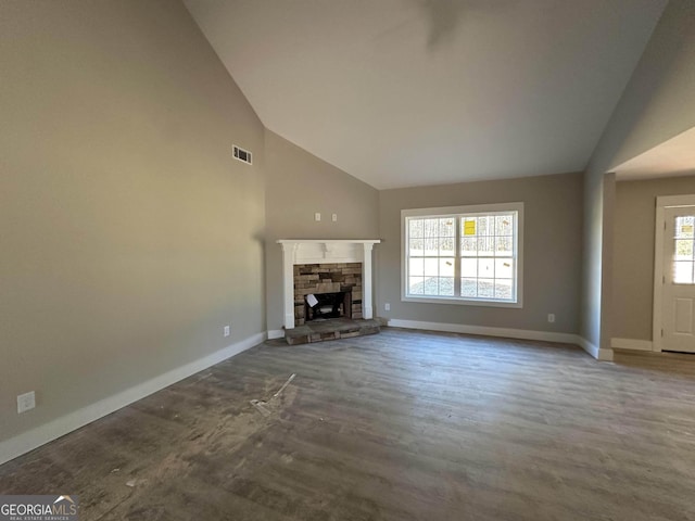 unfurnished living room with hardwood / wood-style flooring, plenty of natural light, a stone fireplace, and vaulted ceiling