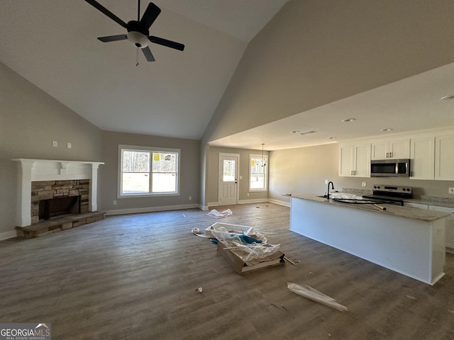 kitchen featuring ceiling fan, dark hardwood / wood-style floors, a fireplace, white cabinetry, and stainless steel appliances