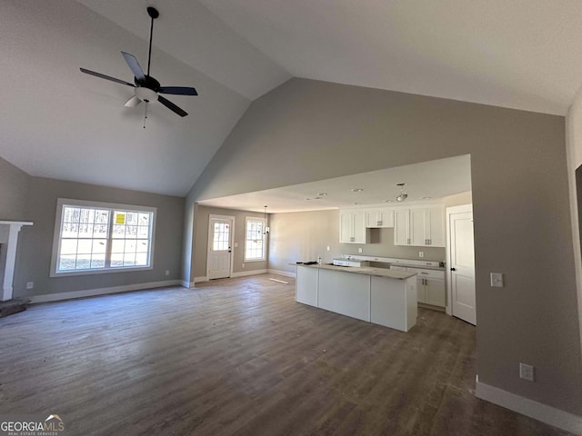 unfurnished living room featuring ceiling fan with notable chandelier, dark hardwood / wood-style flooring, and vaulted ceiling