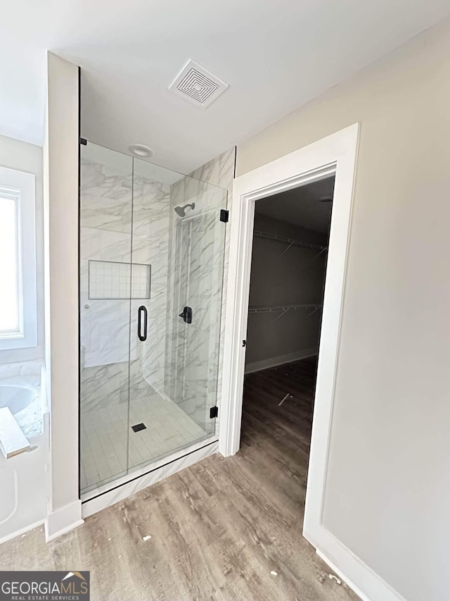 bathroom featuring an enclosed shower and wood-type flooring