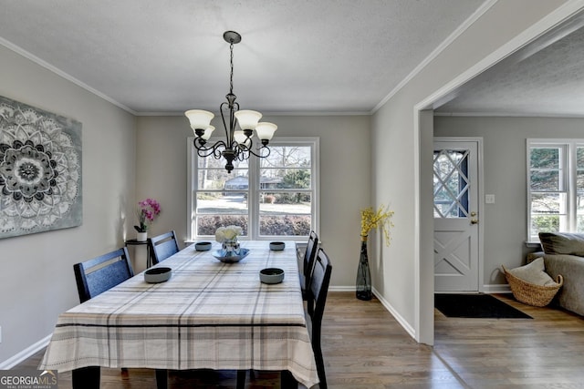 dining area with hardwood / wood-style flooring, an inviting chandelier, ornamental molding, and a textured ceiling