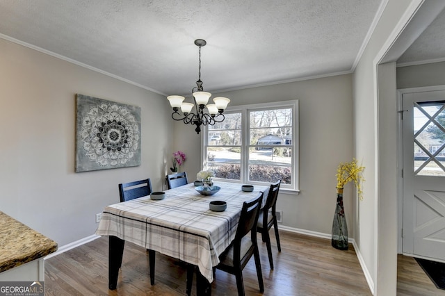 dining area with an inviting chandelier, crown molding, wood-type flooring, and a textured ceiling