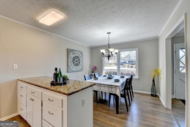 kitchen with decorative light fixtures, a notable chandelier, light hardwood / wood-style floors, crown molding, and white cabinetry