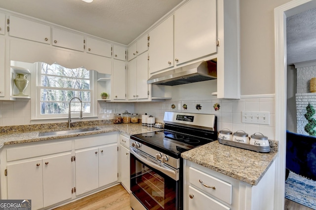 kitchen with white cabinets, stainless steel electric stove, light stone countertops, and sink