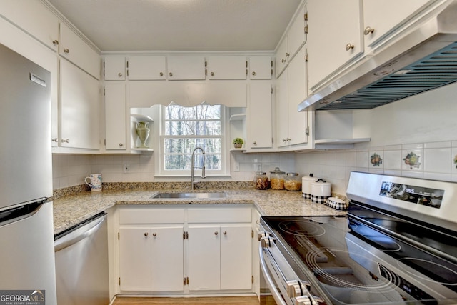 kitchen featuring appliances with stainless steel finishes, white cabinetry, light stone counters, and sink