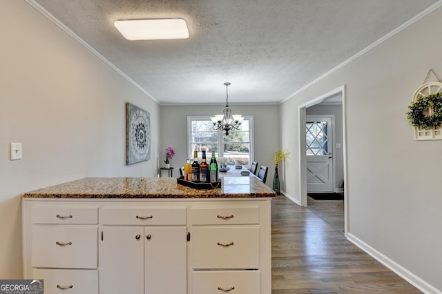 kitchen with white cabinets, an inviting chandelier, ornamental molding, and a textured ceiling