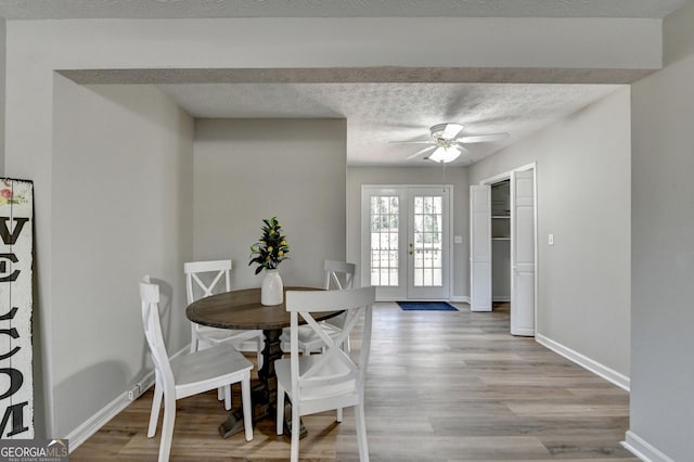 dining space featuring french doors, a textured ceiling, ceiling fan, and light hardwood / wood-style flooring