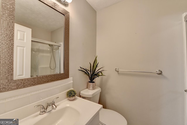 bathroom featuring a textured ceiling, walk in shower, vanity, and toilet